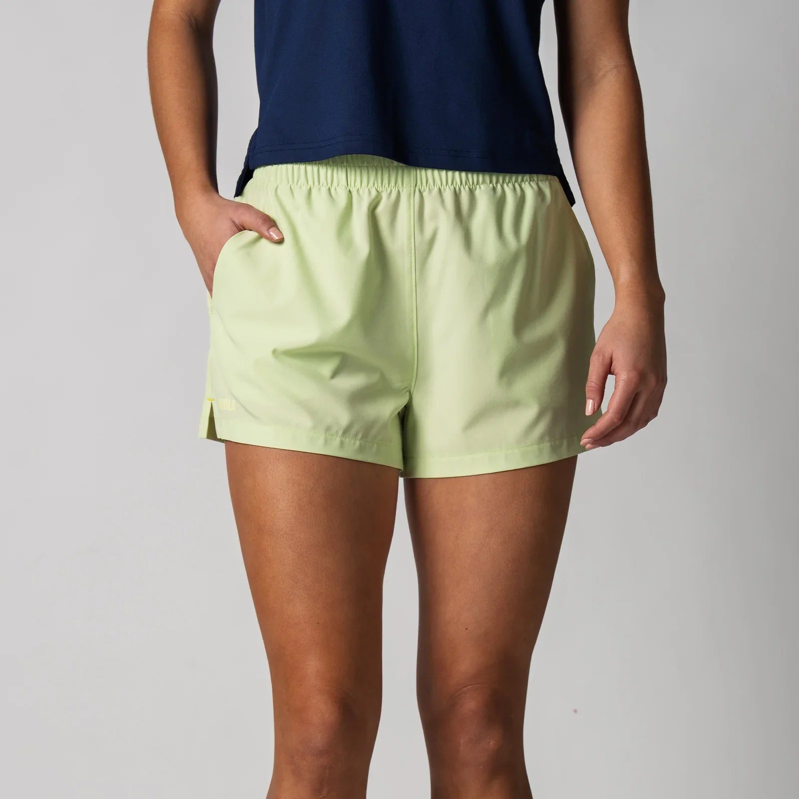 Lime green athletic shorts with side pockets, worn for pickleball or table tennis training