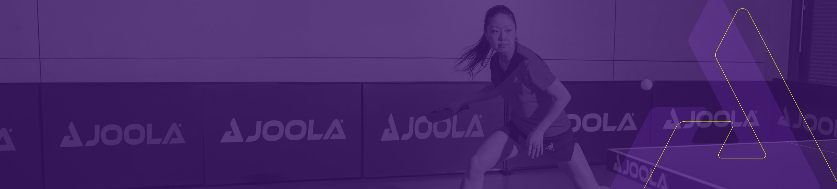 Woman playing table tennis with paddle, focused stance on JOOLA-branded court